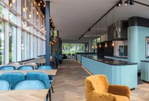 Modern en licht interieur van een restaurant aan het John M. Keynesplein met blauwe accenten en grote raampartijen.